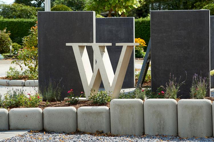 [Translate to Polski:] Blumenbeet mit Buchstabe W aus Beton