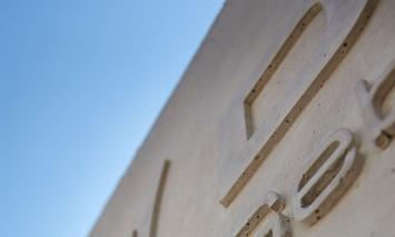 Betonowa ściana z literami na tle błękitnego nieba