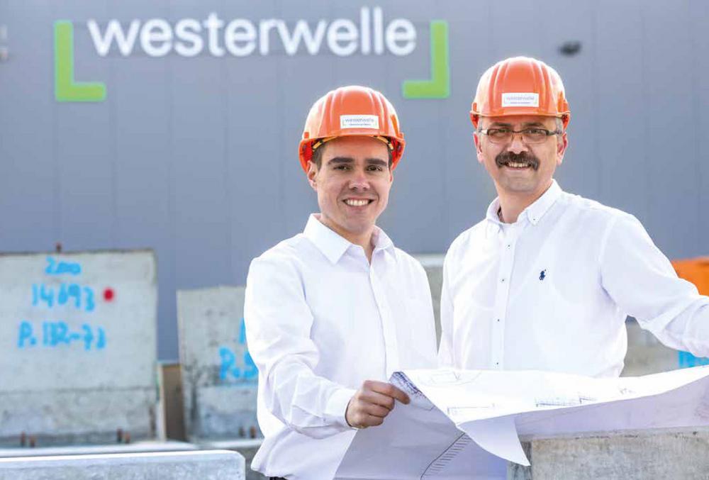 Zwei Mitarbeiter mit Helmen und Bauplan vor Westerwelle-Gebäude