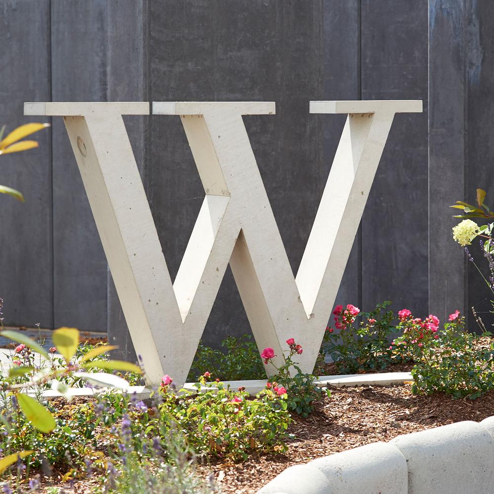 Duża betonowa litera W w kwietniku