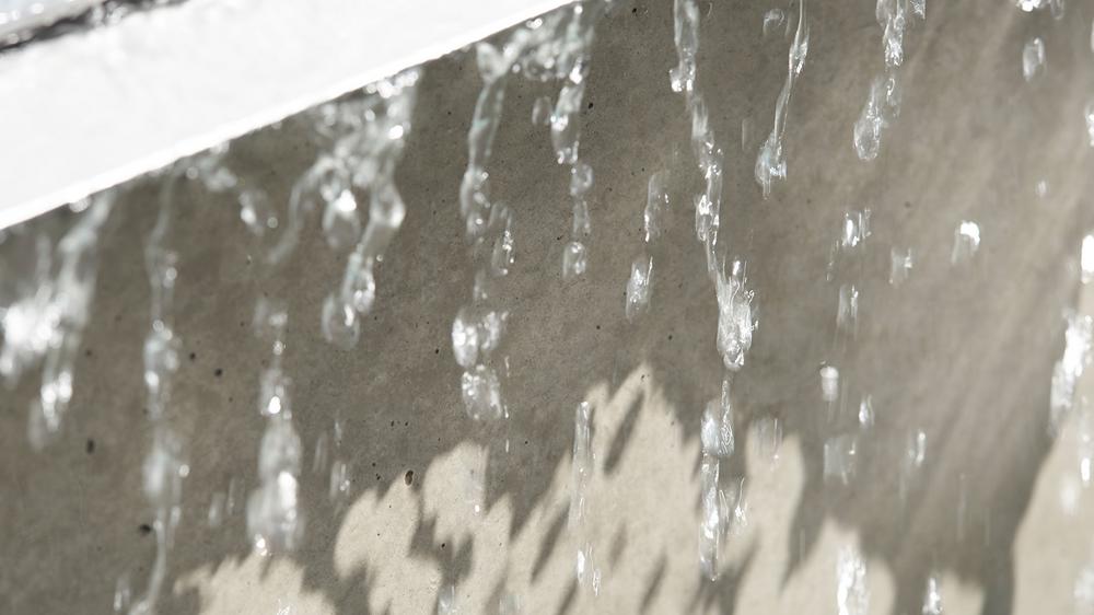 Betonmauer mit abperlenden Wassertropfen